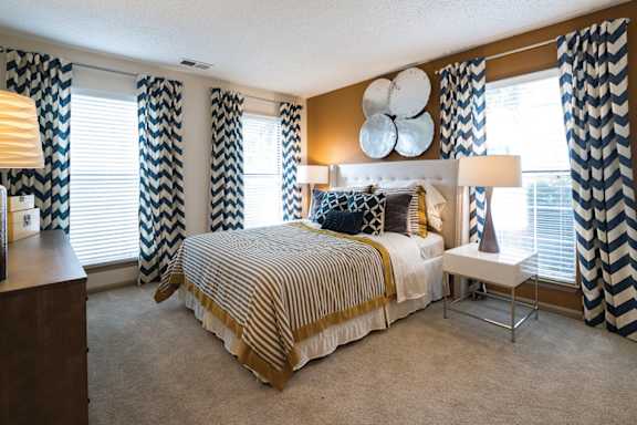 A bedroom with a large bed and a chair.