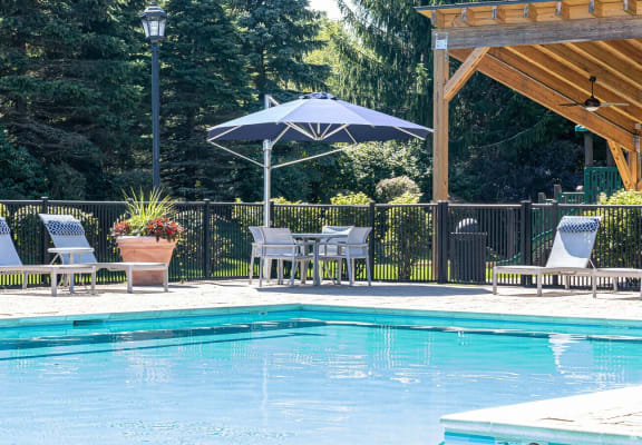 a swimming pool with chairs and umbrellas next to a pool