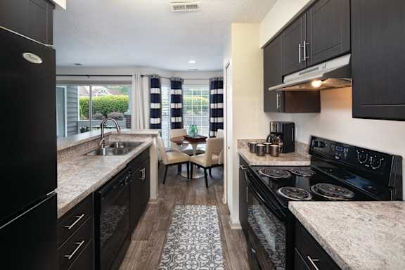 A kitchen with black cabinets and a granite countertop.