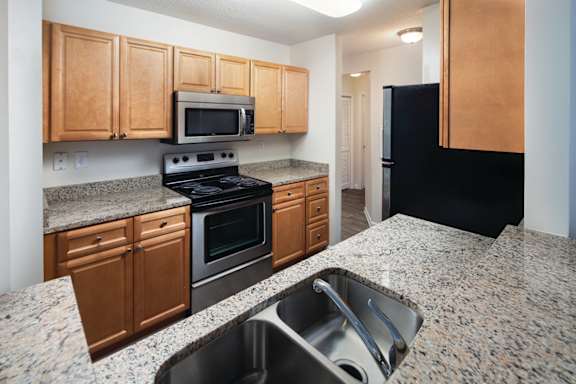 A kitchen with granite countertops and wooden cabinets.