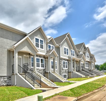 A row of houses with a blue sky and clouds in the background.