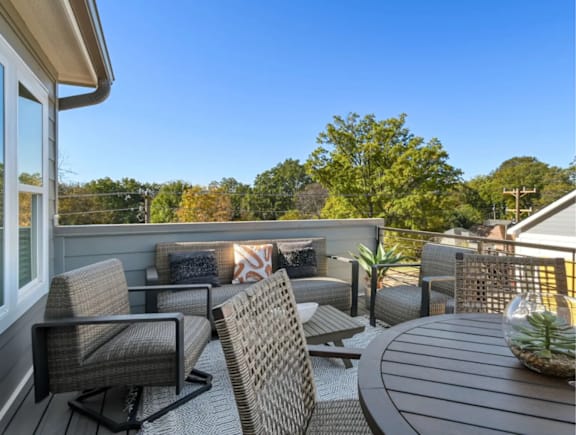 A patio with a table, chairs, and a potted plant.