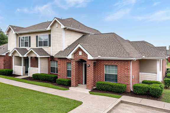 A two-story house with a red brick front and a grey roof.