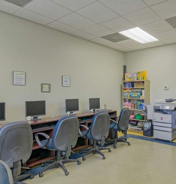 a computer room with desks and chairs and a filing cabinet
