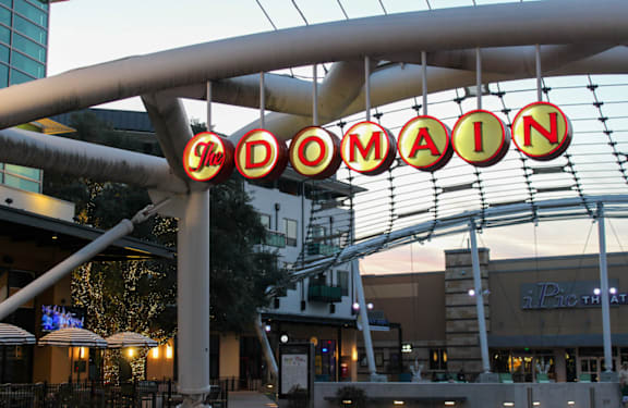 A sign that says "The Domain" hangs from a metal structure.