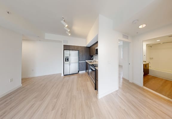 A kitchen with a refrigerator, sink, and cabinets is visible from the living room.