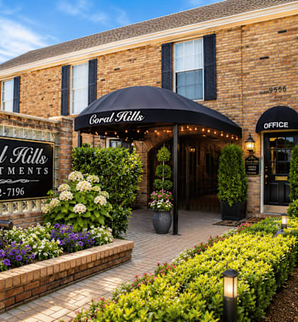 The front of the Coral Hills Apartments building is shown with a sign and a black umbrella.