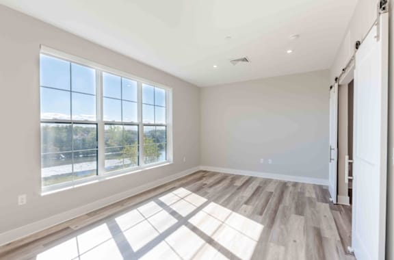 A room with a large window and wooden flooring.