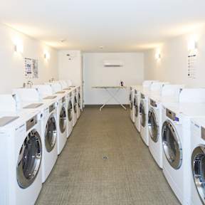 A row of white front load washing machines in a laundromat.