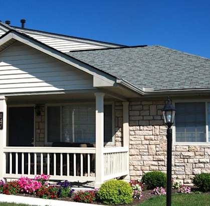A house with a grey roof and a porch with a white railing.