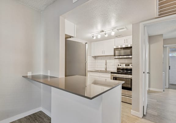 A kitchen with a stainless steel refrigerator and white cabinets.