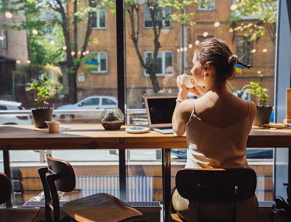 a woman sitting at a table in a restaurant looking out a window