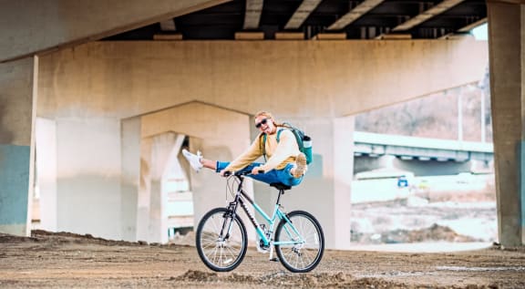 a woman riding a bike under a bridge