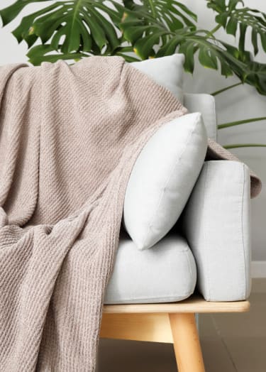 a blanket draped over a couch with pillows and a plant