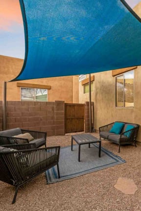 a patio with chairs and a blue umbrella