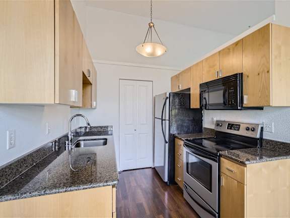 A kitchen with wooden cabinets and black appliances.