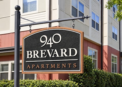 A sign for 940 Brevard Apartments is shown in front of a building.
