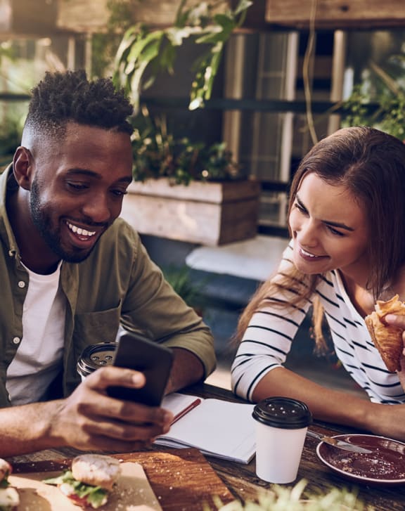 a man and woman sitting at a table looking at a cell phone