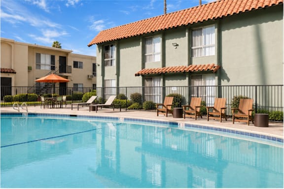 A swimming pool in front of a building with a red tile roof.
