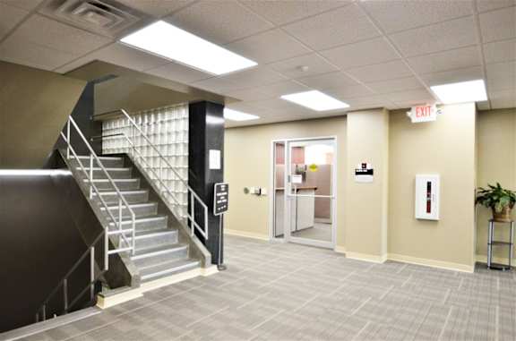 A hallway with a staircase and an exit sign.