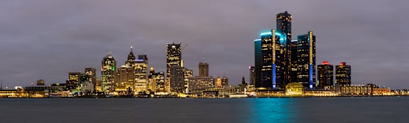 A city skyline at night with a body of water in the foreground.