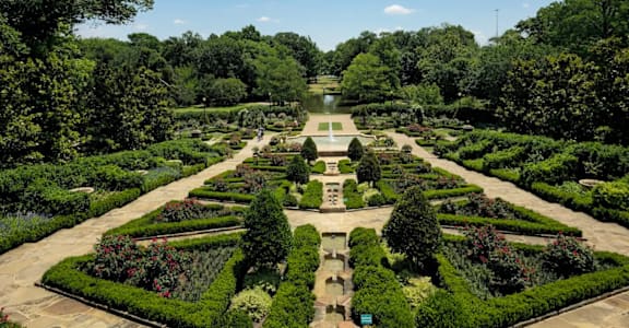 A beautifully manicured garden with a fountain in the center.