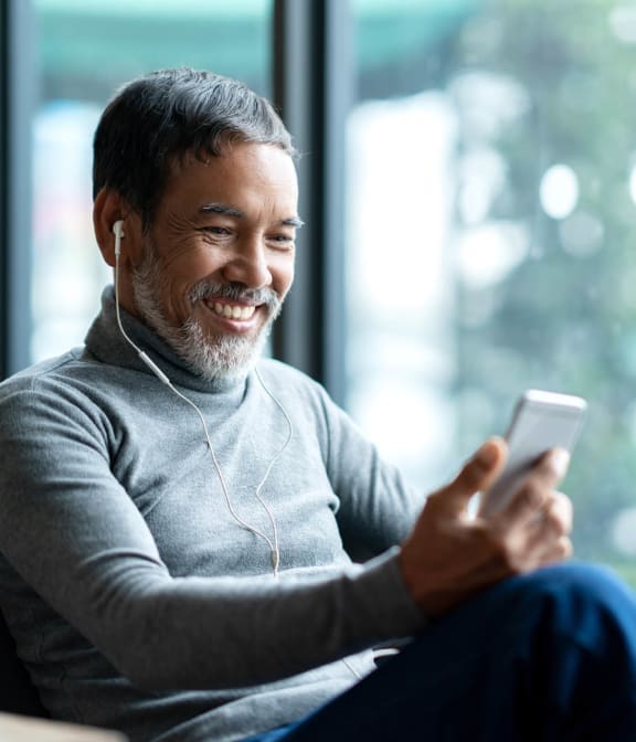 Man smiling at phone while listening to music
