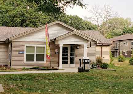 A small building with a grey roof and a white door.