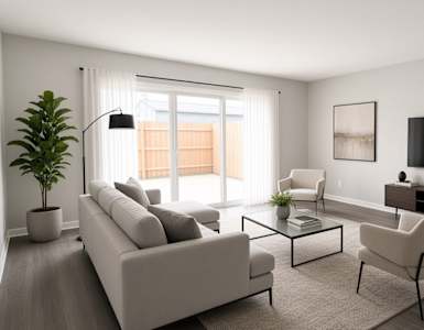 A living room with a grey sofa, a white armchair, a glass coffee table, and a television on the wall.