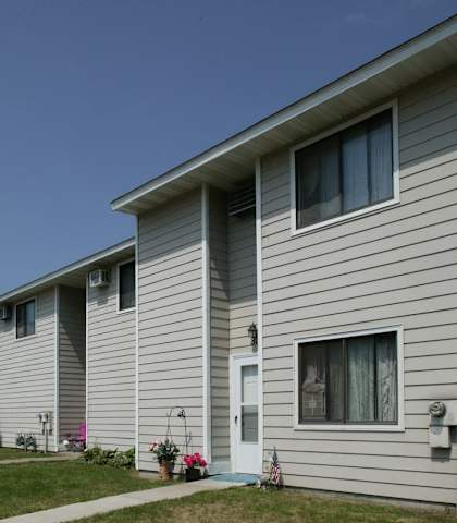 a row of houses with white siding and grass