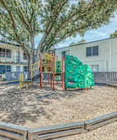 A playground with a green slide and a red and yellow structure.
