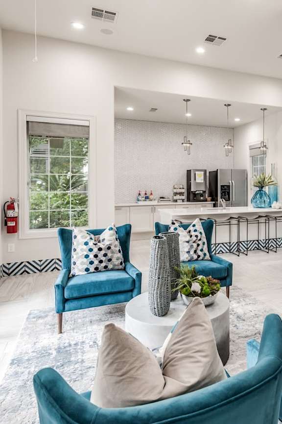 A living room with blue chairs and a white rug.