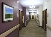 Thumbnail 6 of 6 - A hallway with brown doors and a painting on the wall.