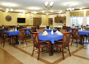 Thumbnail 4 of 6 - A dining room with tables covered in blue cloth and wooden chairs.