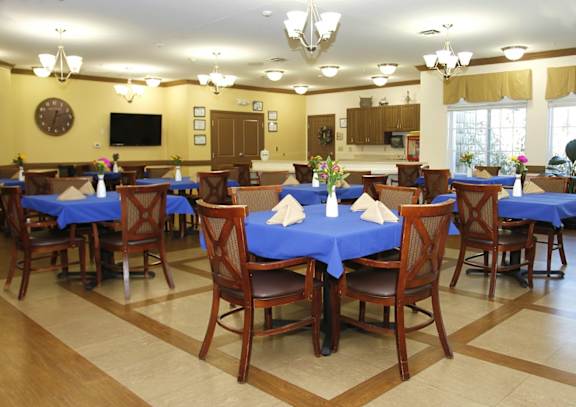 A dining room with tables covered in blue cloth and wooden chairs.