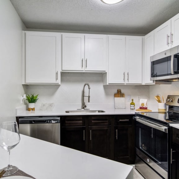 our apartments offer a modern kitchen with white cabinets and black appliances