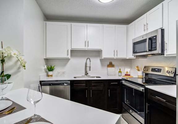 our apartments offer a modern kitchen with white cabinets and black appliances