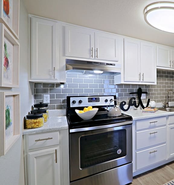 a kitchen with white cabinets and stainless steel appliances at Spring Meadow Apartments, Glendale, AZ