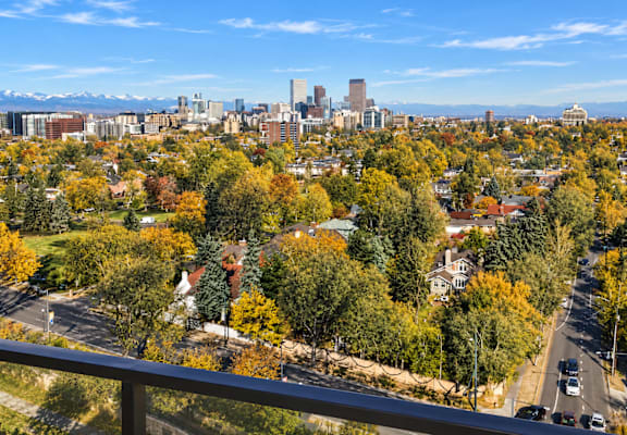 A cityscape with a mix of residential and commercial buildings, surrounded by trees with autumn foliage.