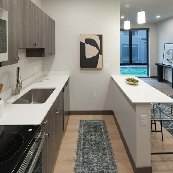 a living room with a tv and a kitchen with a table and chairs