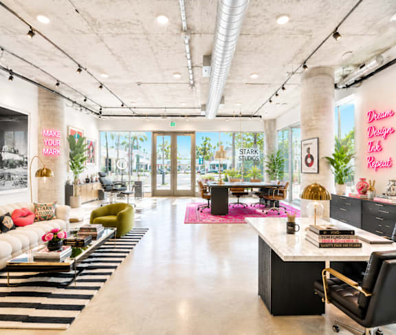 A modern live/work office space with a long white couch and a black and white striped rug at Fusion Hollywood Apartments.