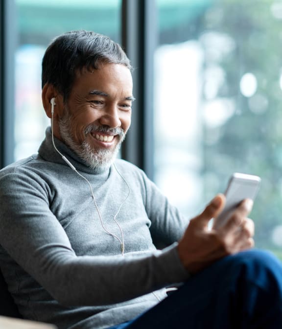 Man smiling at phone while listening to music