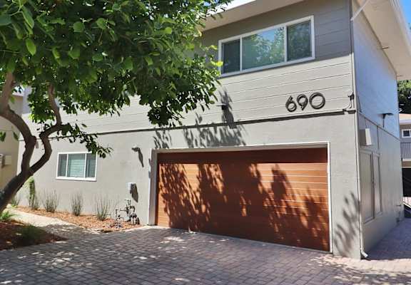 a garage door in front of a white house with a tree