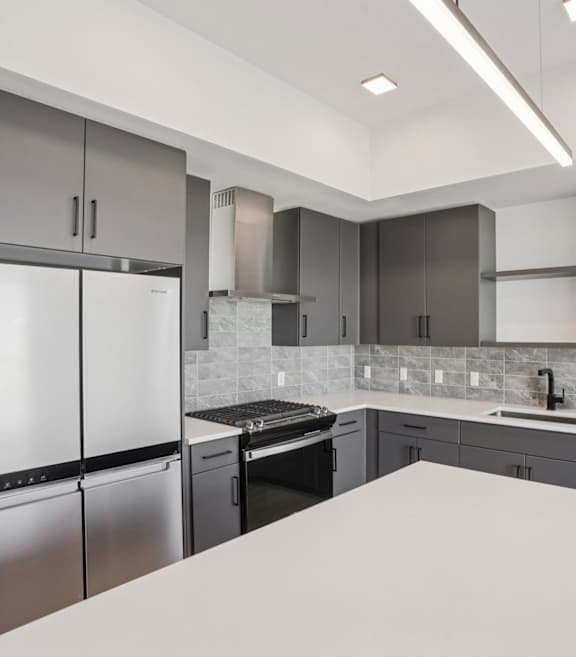 A modern kitchen with a white countertop and stainless steel appliances.