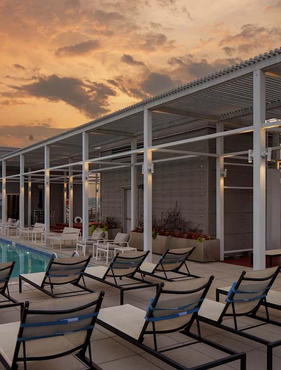 A poolside patio with chairs and a roof.