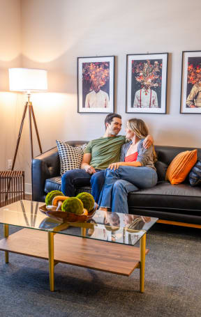a couple sits on a couch with their arms around each other