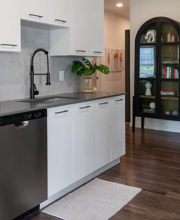 A kitchen with white cabinets and a black dishwasher.