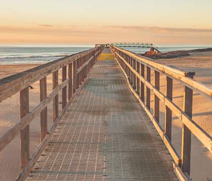 A wooden boardwalk leads to a beach.