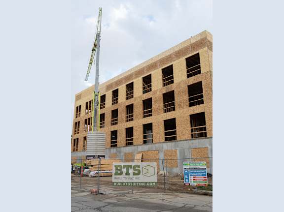 A building under construction with a crane on the left side.