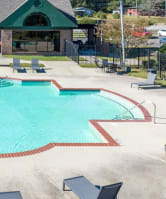 a swimming pool with chairs and a building in the background